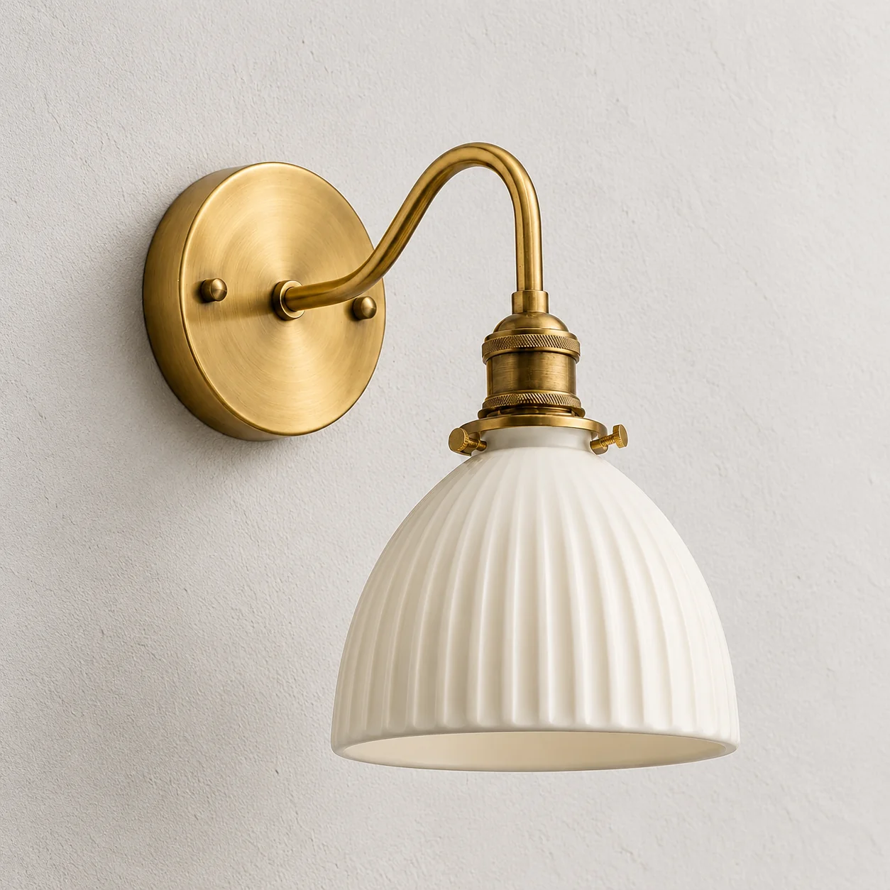Ivory fluted ceramic shade with a curved brass-toned arm and round wall backplate
