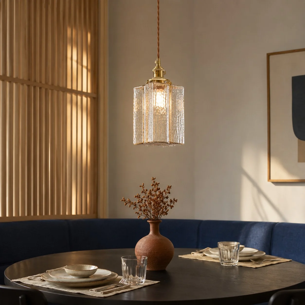 Jewel textured glass cube pendant hanging over a round dining table in a warm modern room