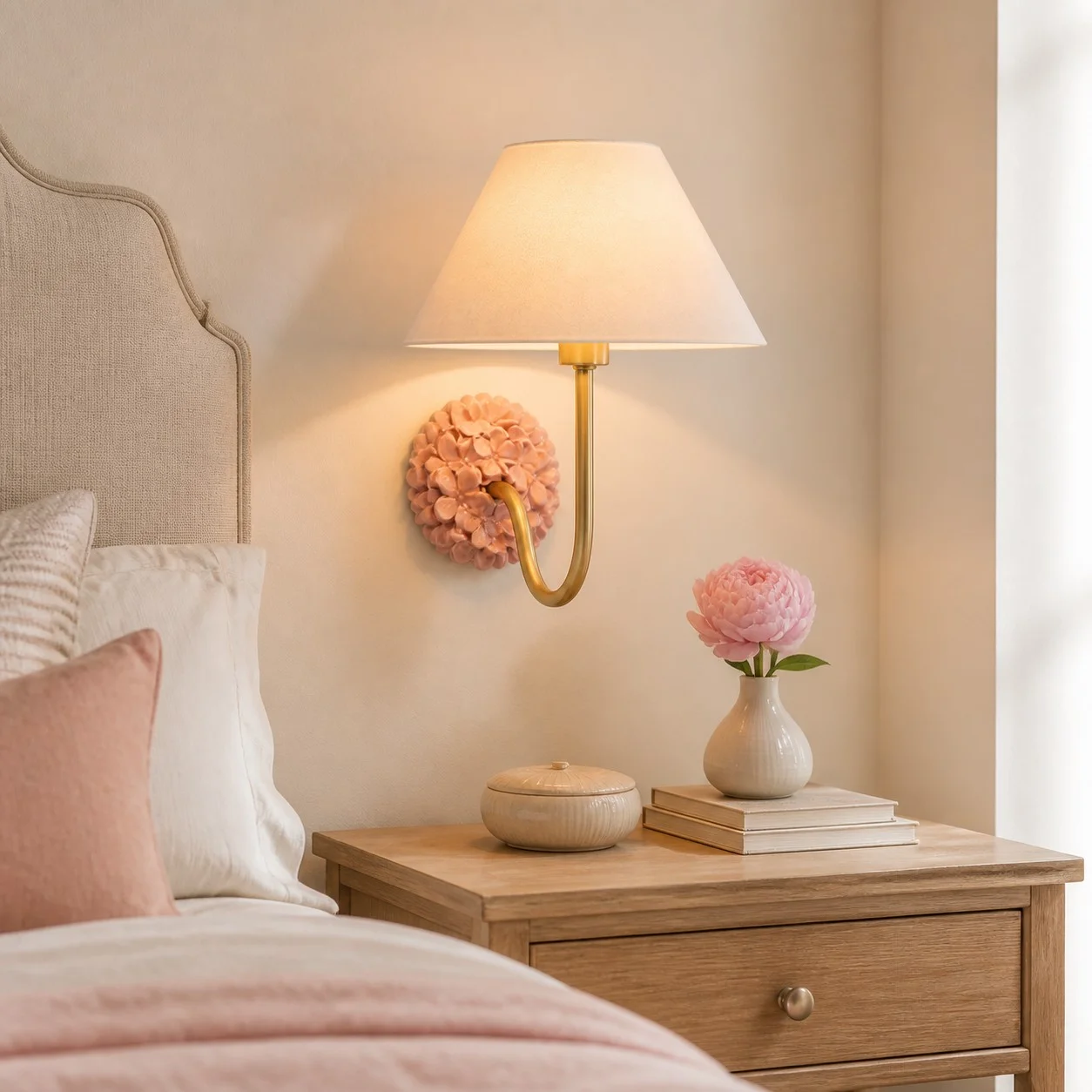 Florienne pink bedside wall sconce beside a linen headboard and wood nightstand