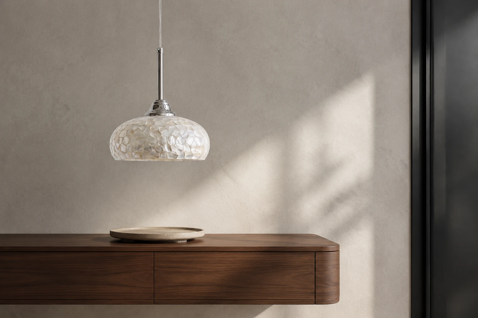 Chrome mother-of-pearl pendant above a walnut entry console