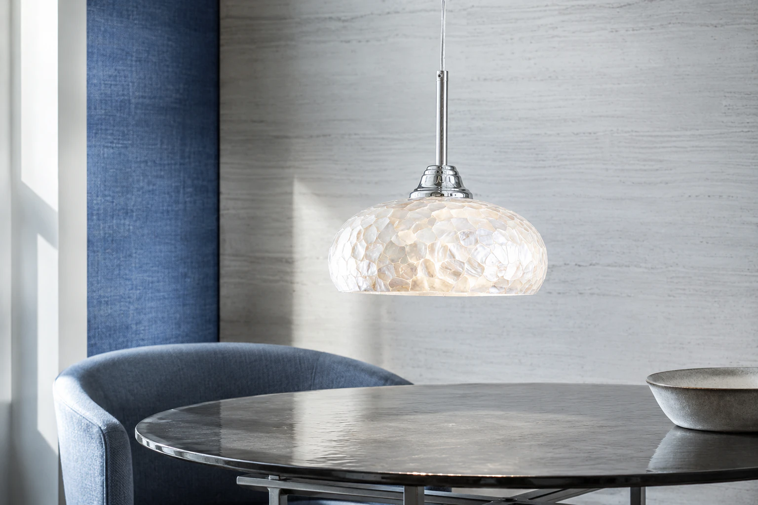 Chrome and white mother-of-pearl mosaic dome pendant above a compact blue-gray dining nook