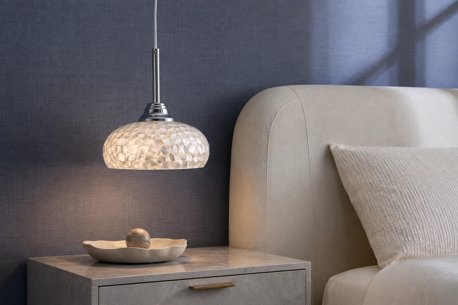 Chrome mother-of-pearl pendant beside an upholstered bed