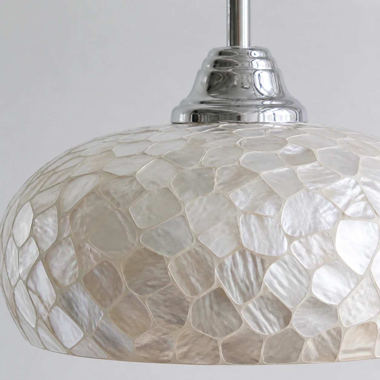 Close view of irregular white mother-of-pearl shell mosaic with polished chrome hardware