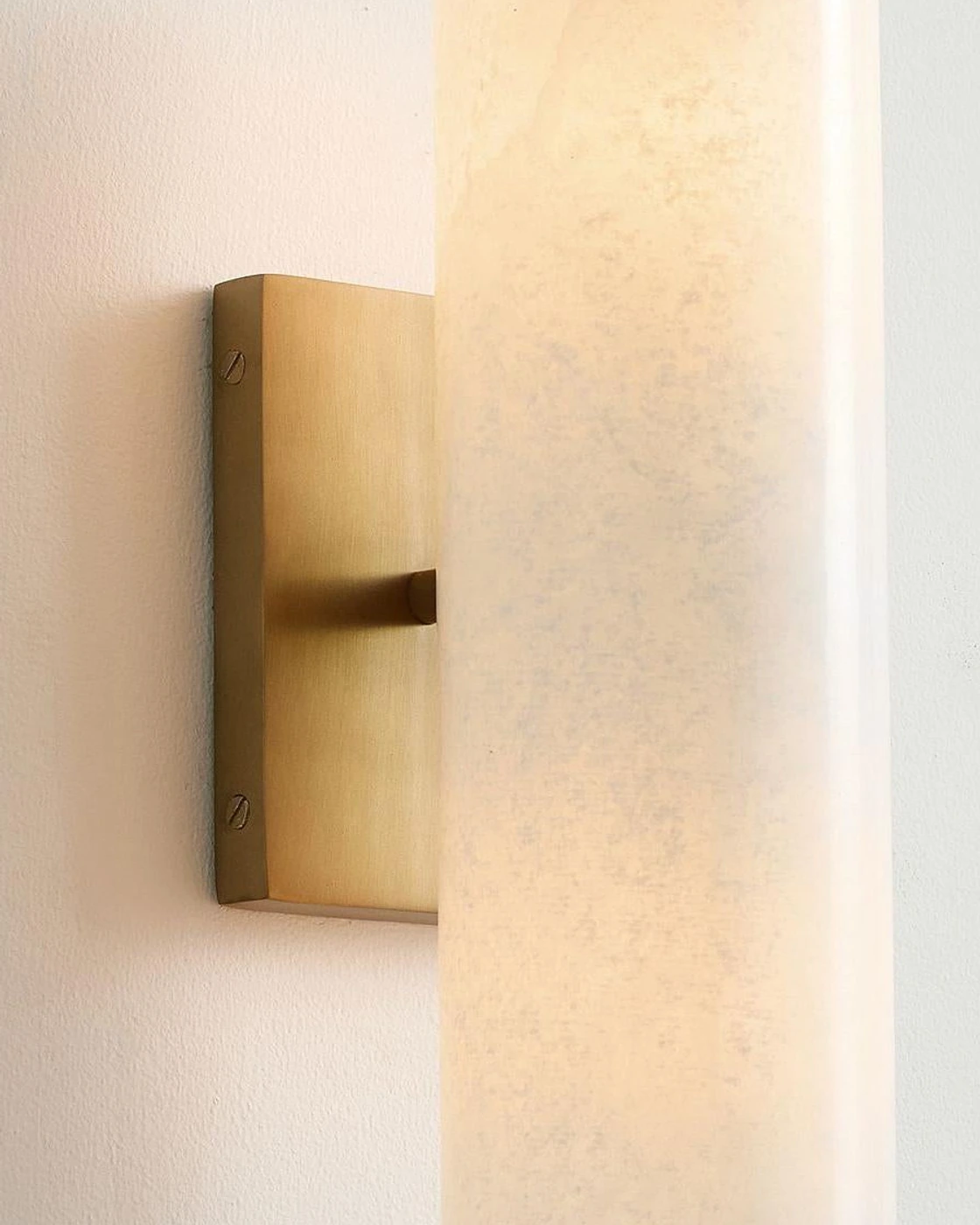 Oblique close detail of the Doran sconce backplate, centered stem and alabaster cylinder