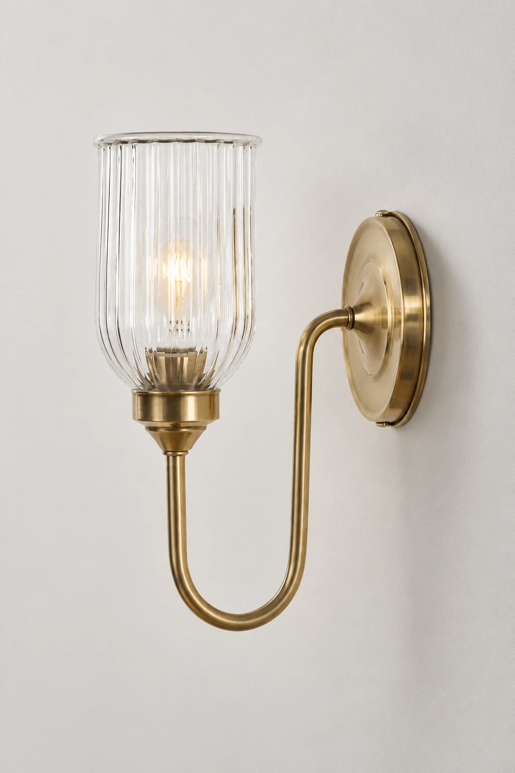 Complete antique brass Menae ribbed glass wall sconce on a neutral studio wall