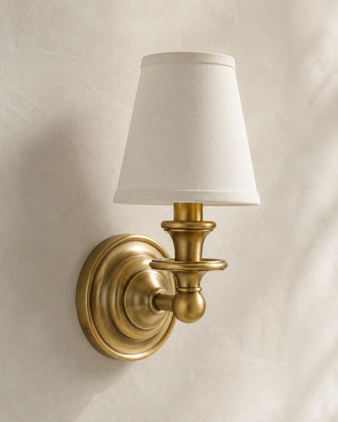 Antique Brass wall sconce mounted flush to a plaster wall
