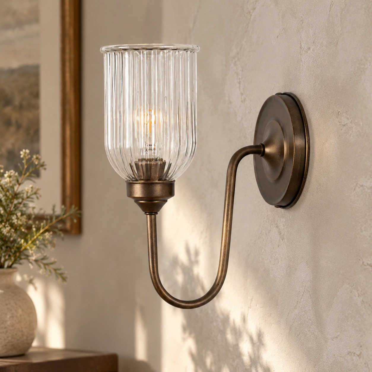 Burnished brass Menae wall sconce showing its round backplate and continuous U-shaped arm