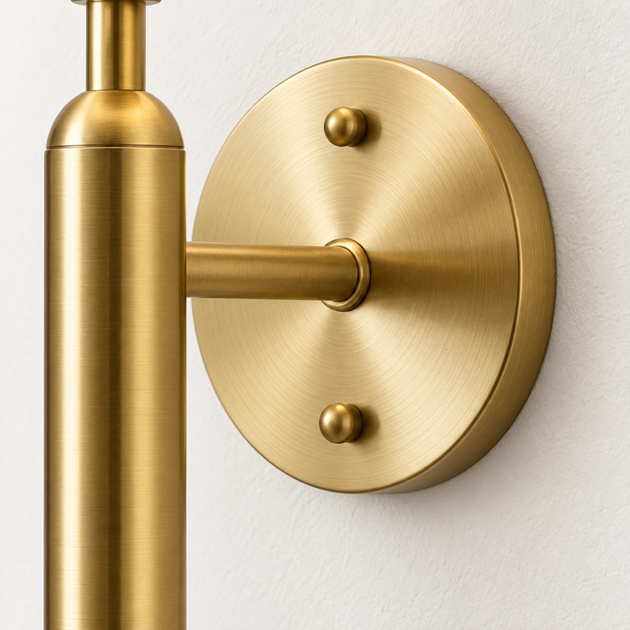 Round brass backplate with two screw caps and a short wall arm