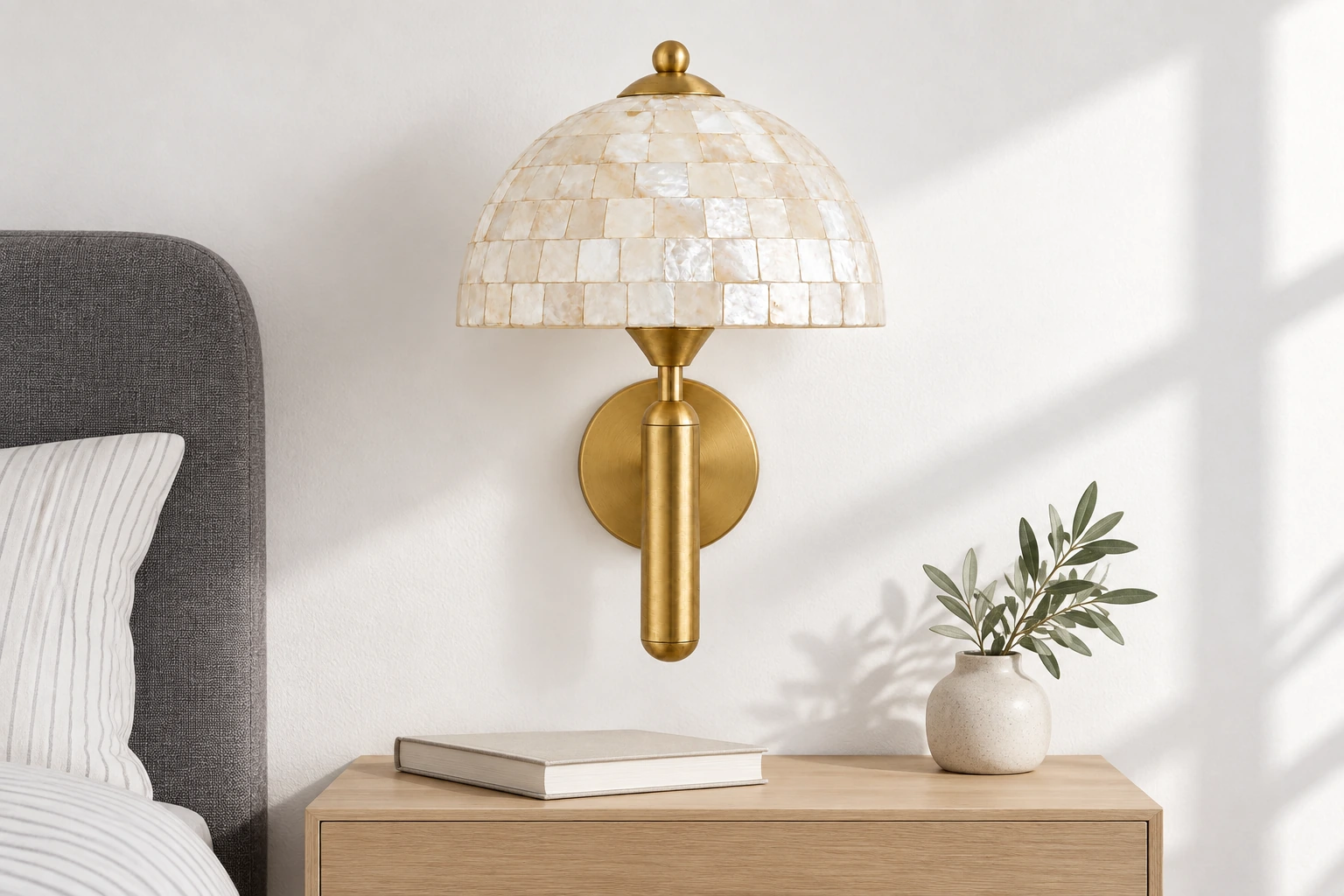 Gold shell wall sconce above a bedside table in a daylight bedroom