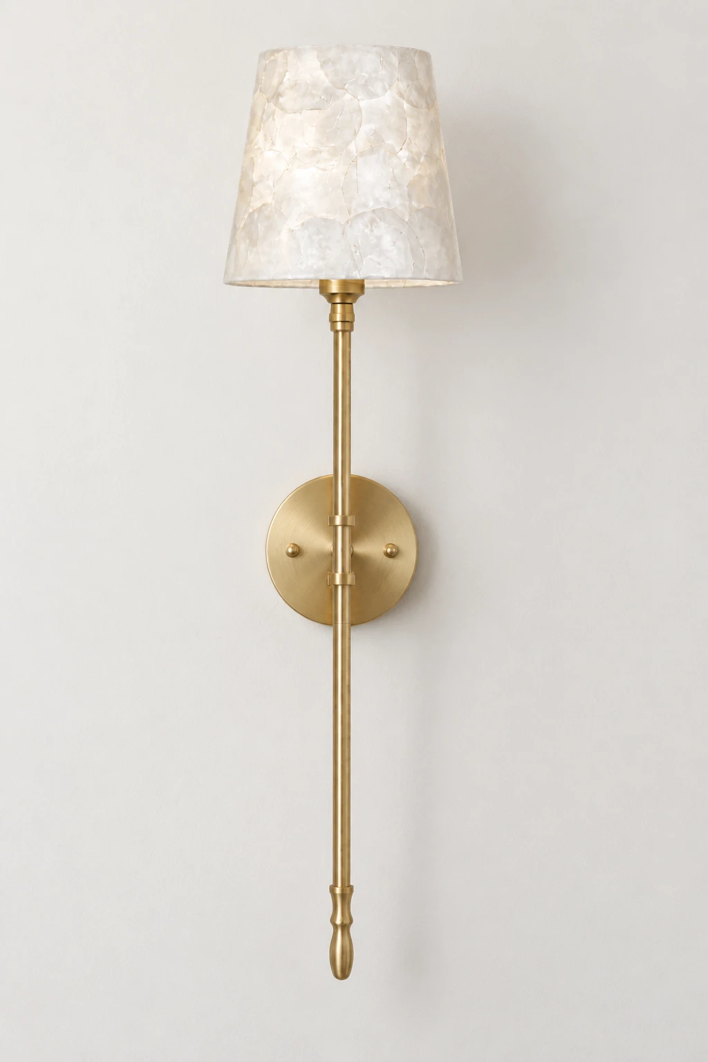 Full studio view of the single brass and shell wall sconce on a neutral wall