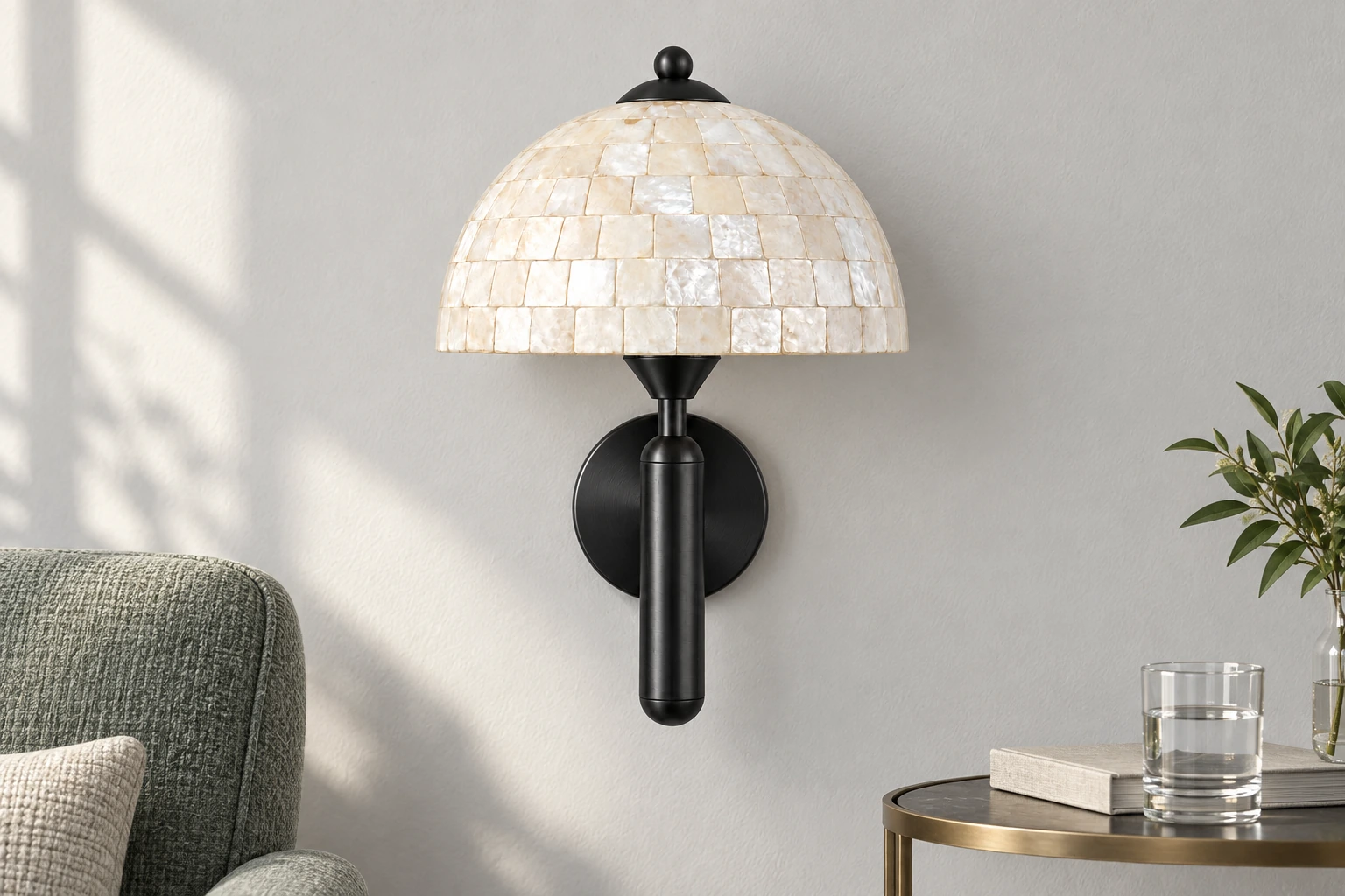 Black shell wall sconce beside a muted green reading chair