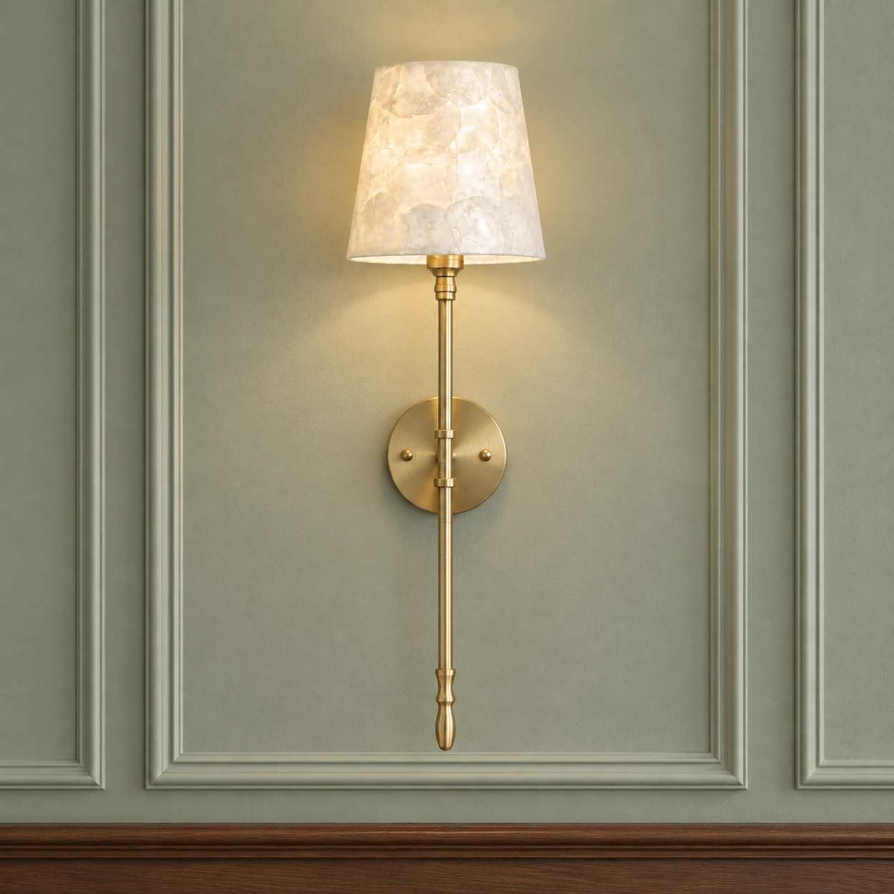 Full frontal view of the brass and ivory shell sconce on a sage paneled wall