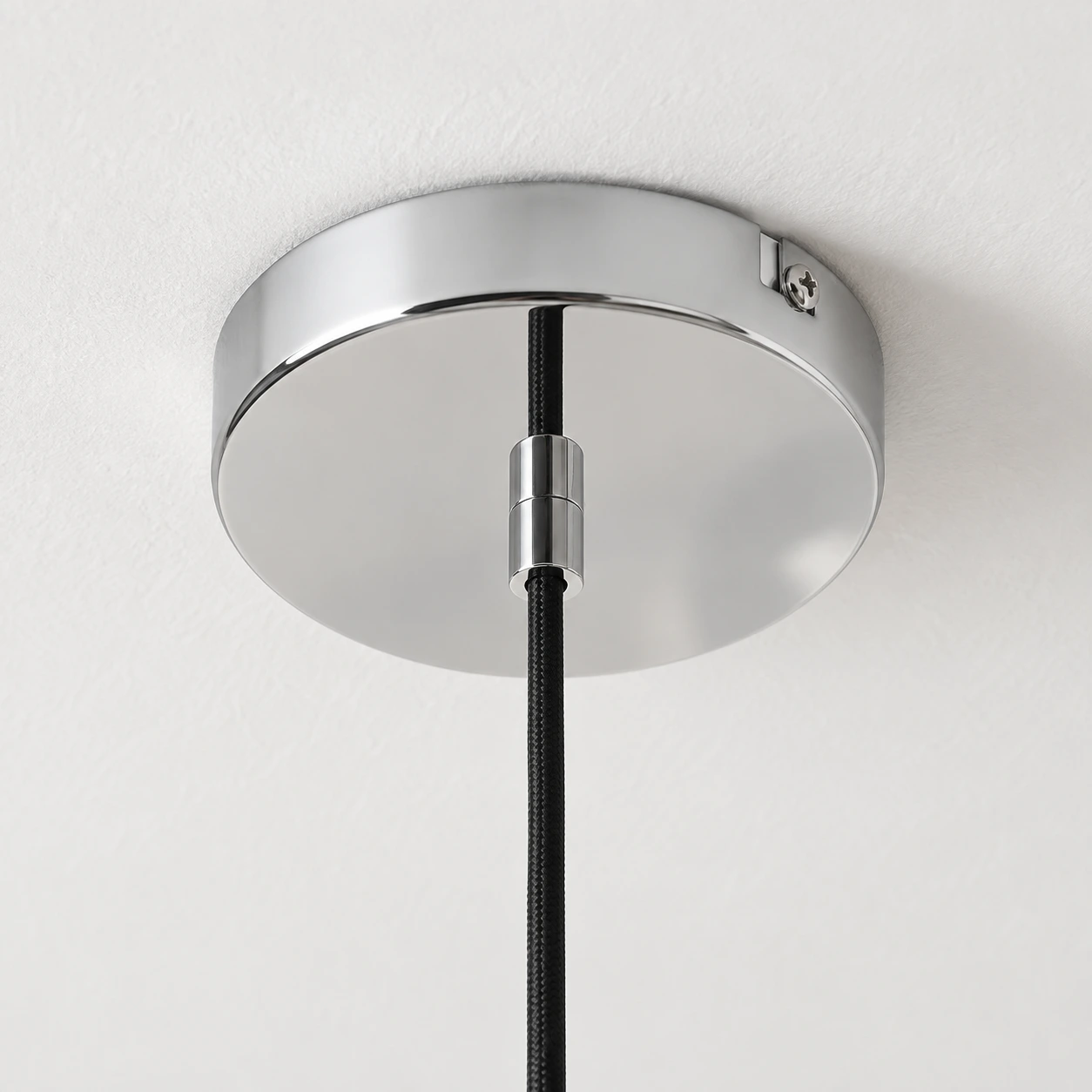 Chrome ceiling canopy fitted flush to a white ceiling with a central black cord