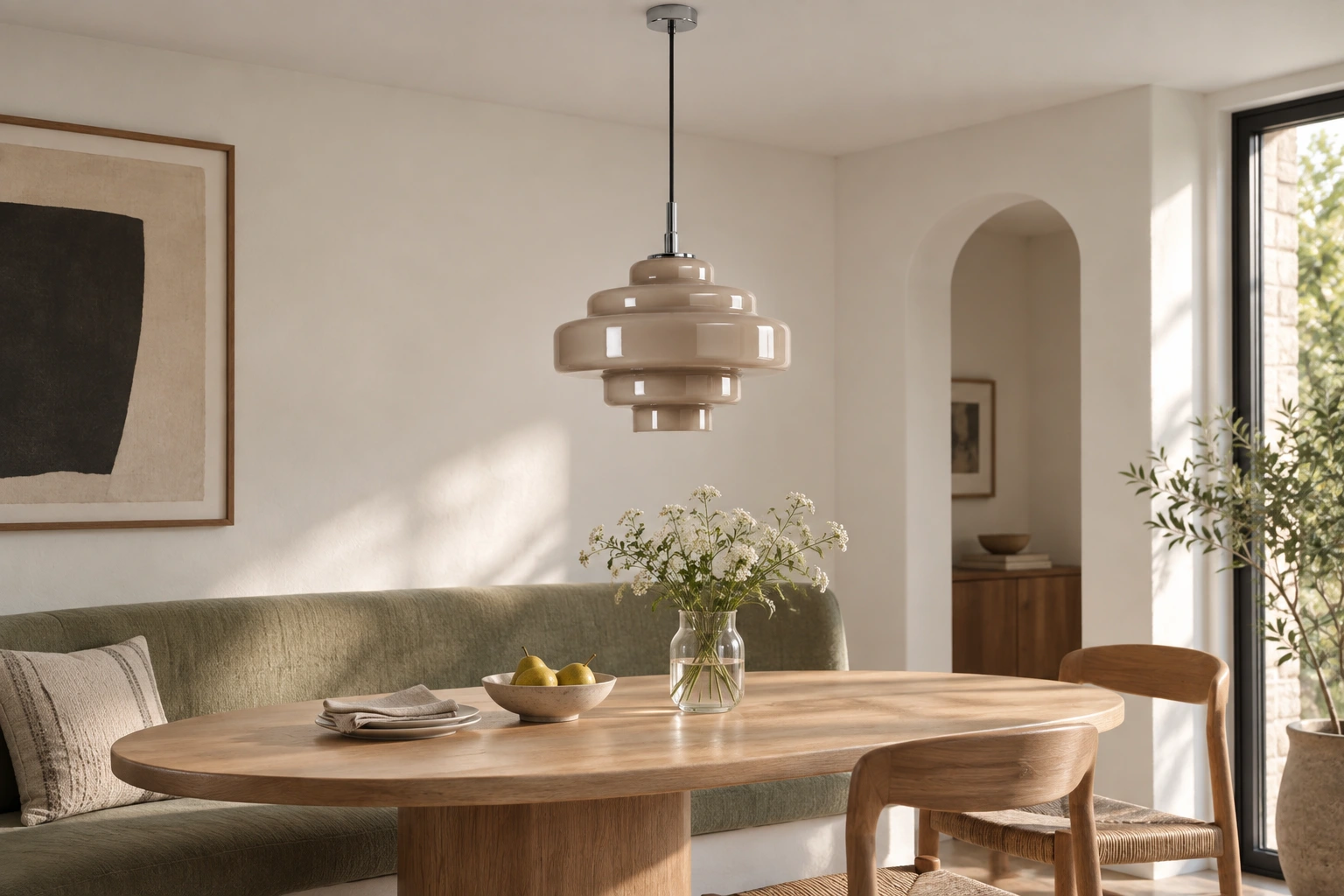 Taupe macaron pendant over an oval dining table beside a sage banquette