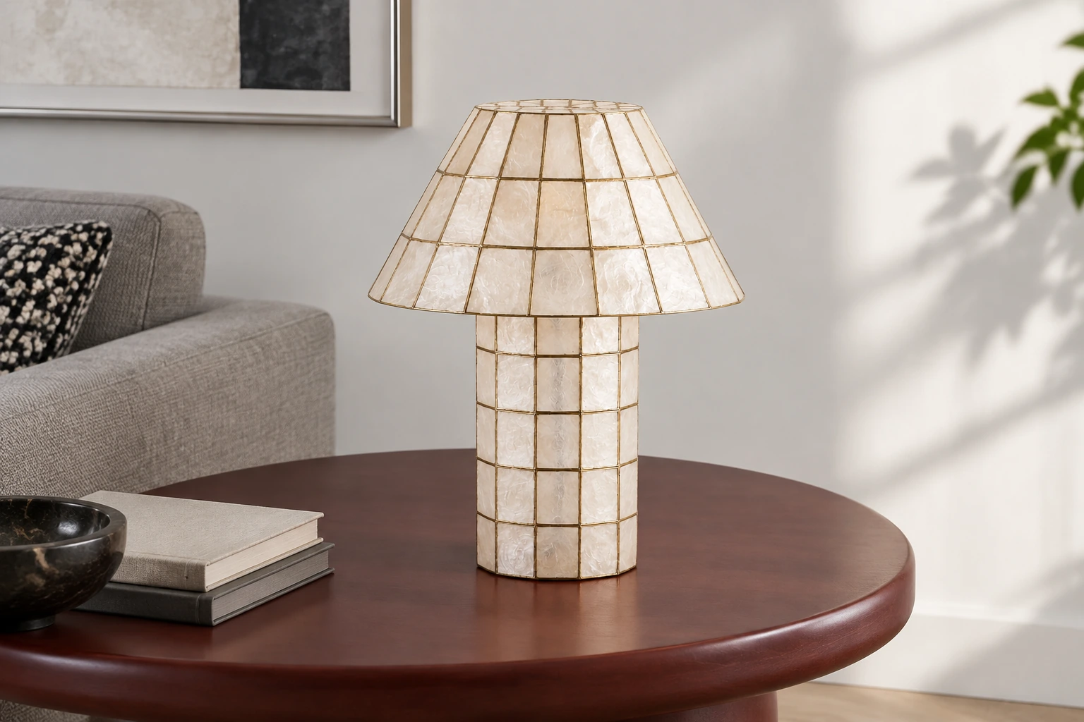 Ivory shell lamp on a dark side table beside a gray sofa