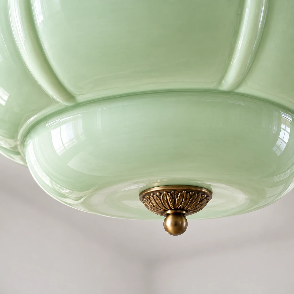 Low-angle detail of the light-green lower bowl and leaf-patterned finial