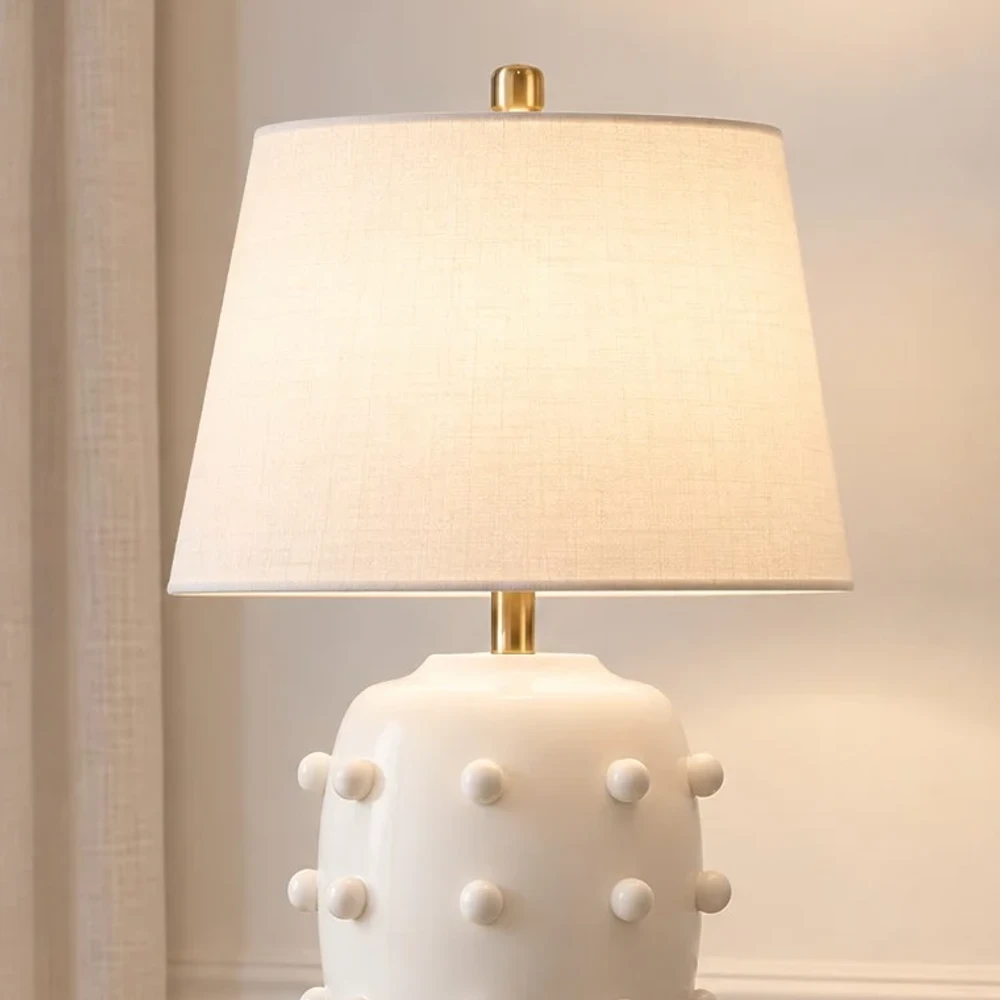Close view of the white fabric shade and brushed brass lamp neck